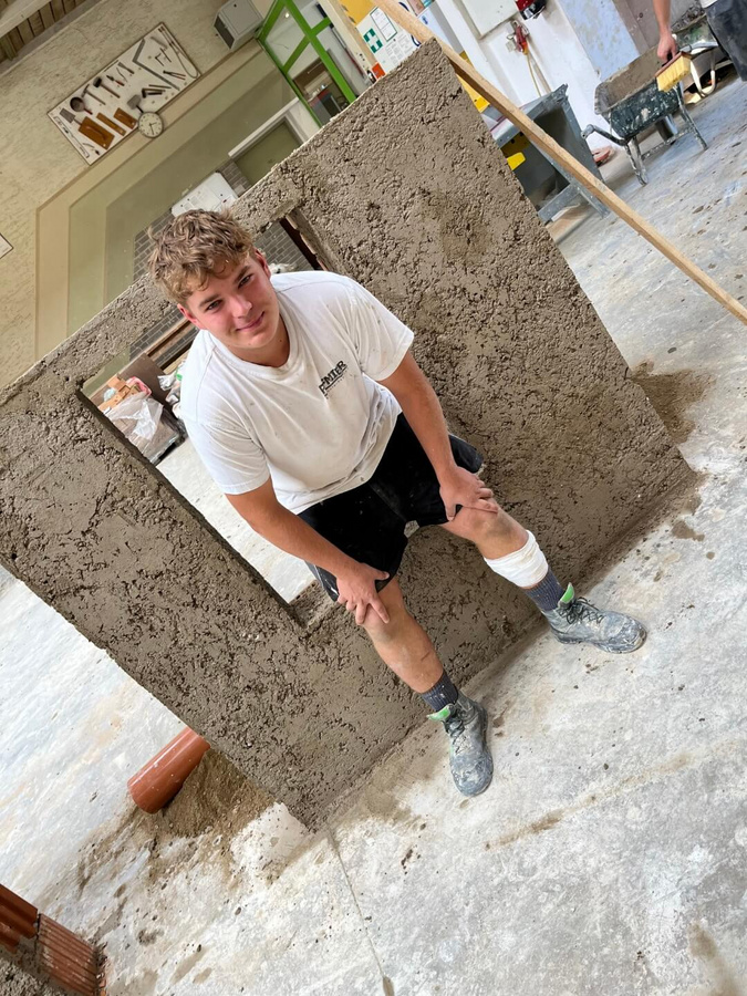 Ein weiterer Pfnier-Lehrling posiert vor seiner Mauer und freut sich über die bestandene Abschlussprüfung.