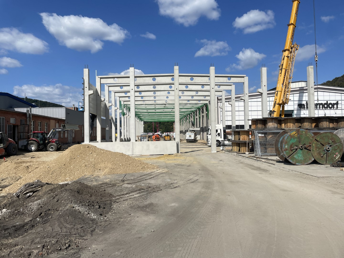 Betonrahmen eines im Bau befindlichen Gebäudes auf einer großen Baustelle mit Kränen und schweren Maschinen.