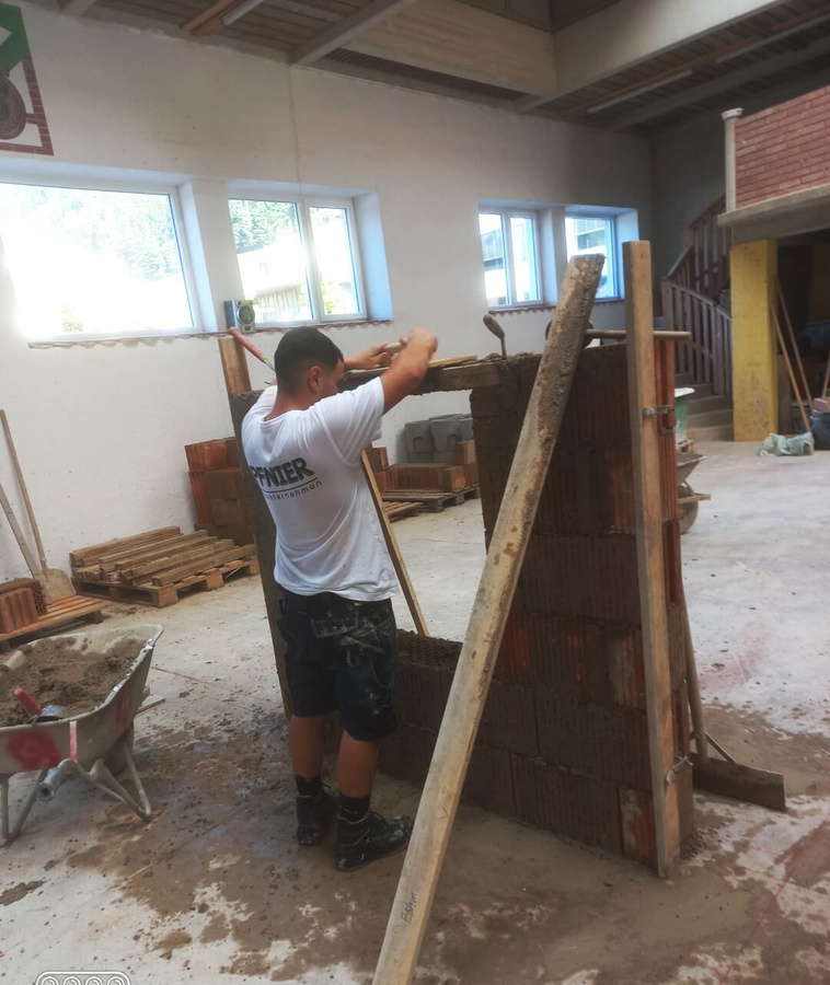 Ein Lehrling von Pfnier arbeitet konzentriert an einer Mauer während der Lehrabschlussprüfung in der Bauakademie Übelbach.