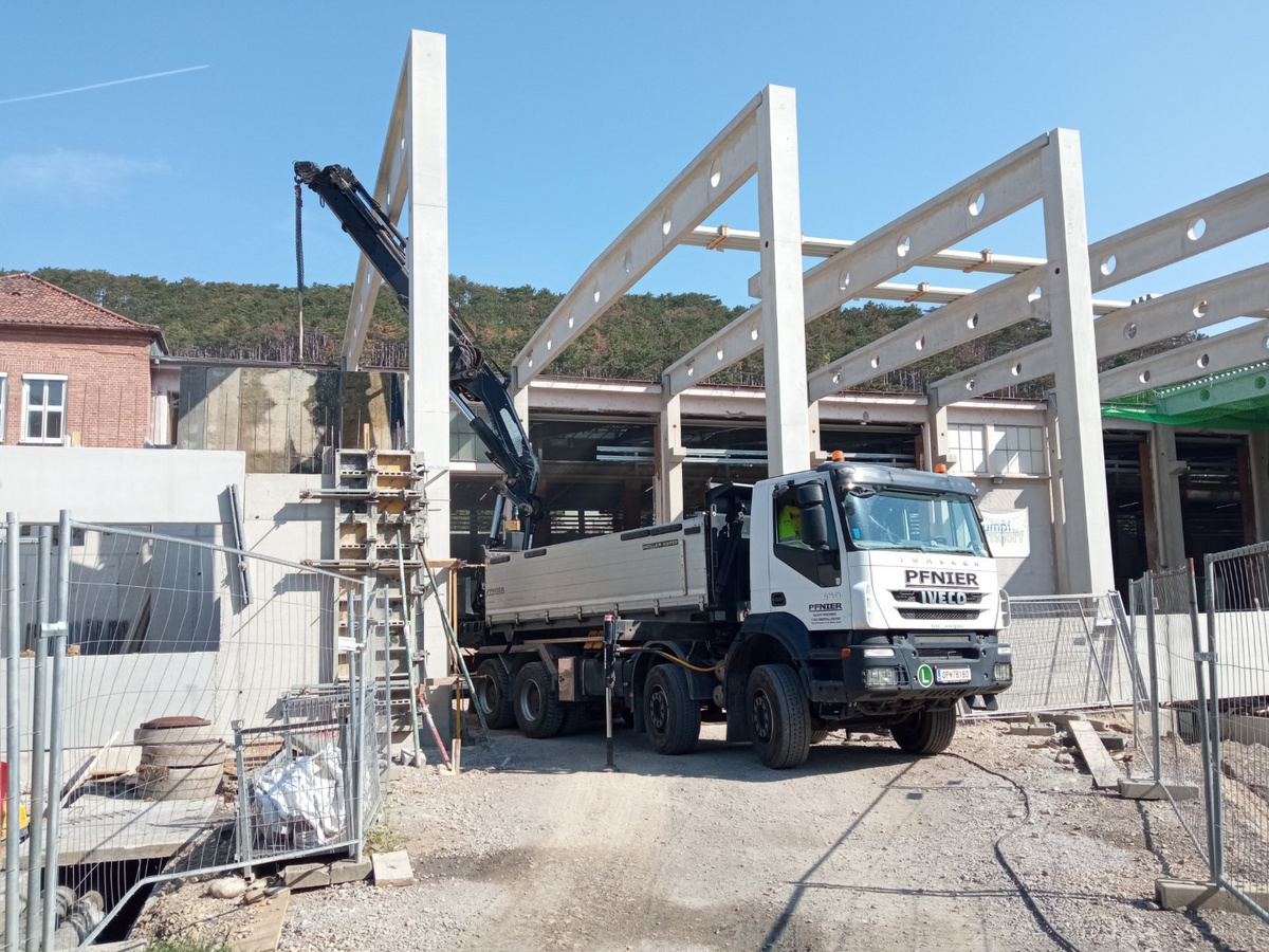 LKW von Pfnier & Co vor einem im Bau befindlichen Industriegebäude mit Betonstützen.